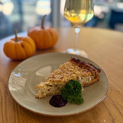 Quiche mit einem Glas Weisswein und kleinen Kürbissen
